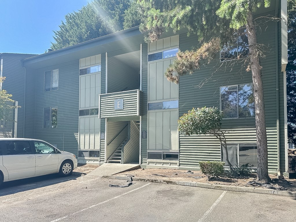 A white car is parked in front of a grey building.