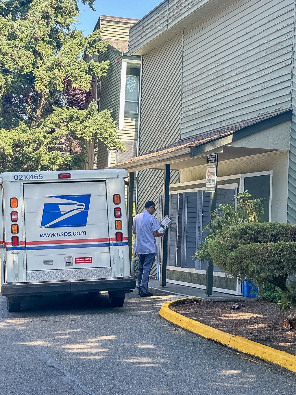 A mail truck is parked on the street in front of a house.