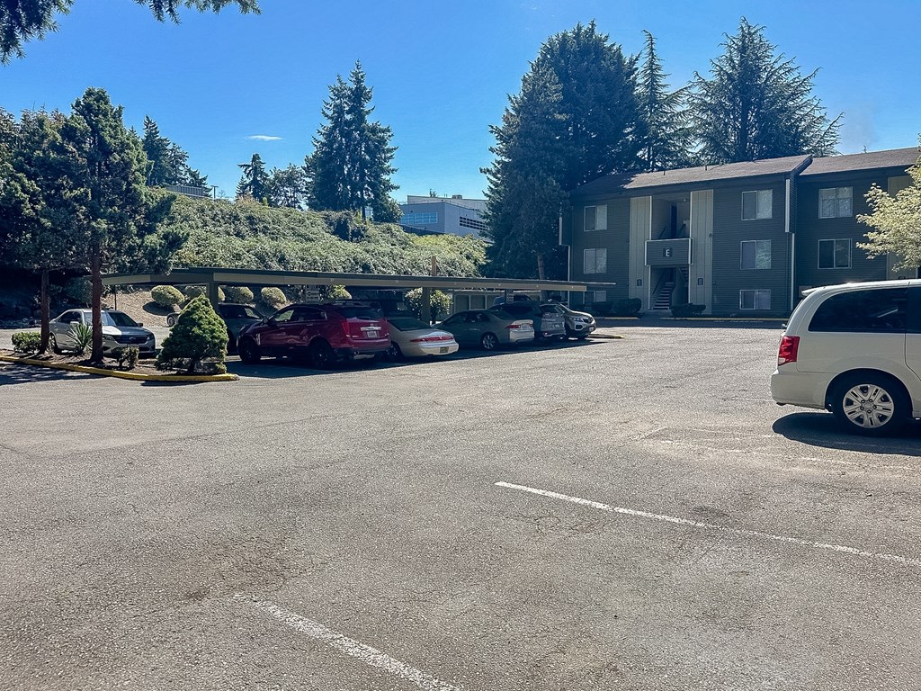 A parking lot with cars and a white van in front of a building.