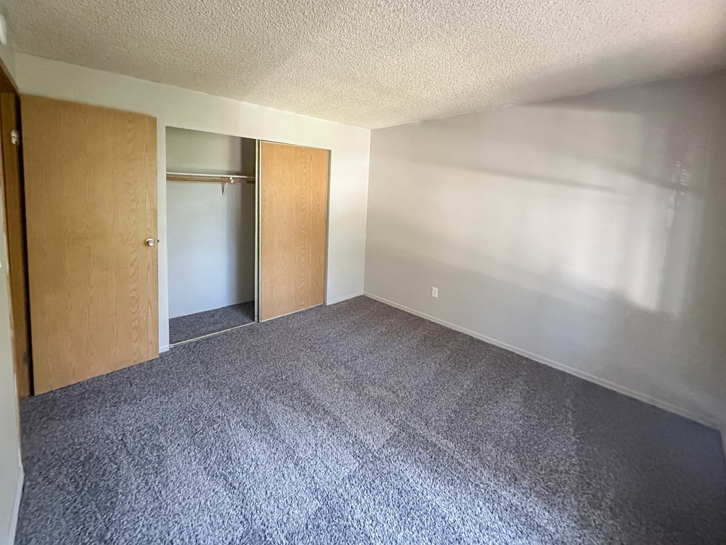 A room with a carpeted floor and two open doors.