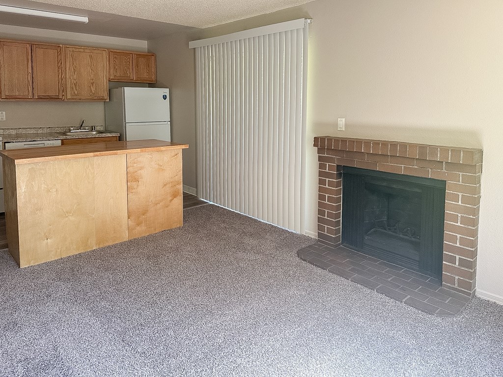 A kitchen with a refrigerator, sink, and a fireplace.