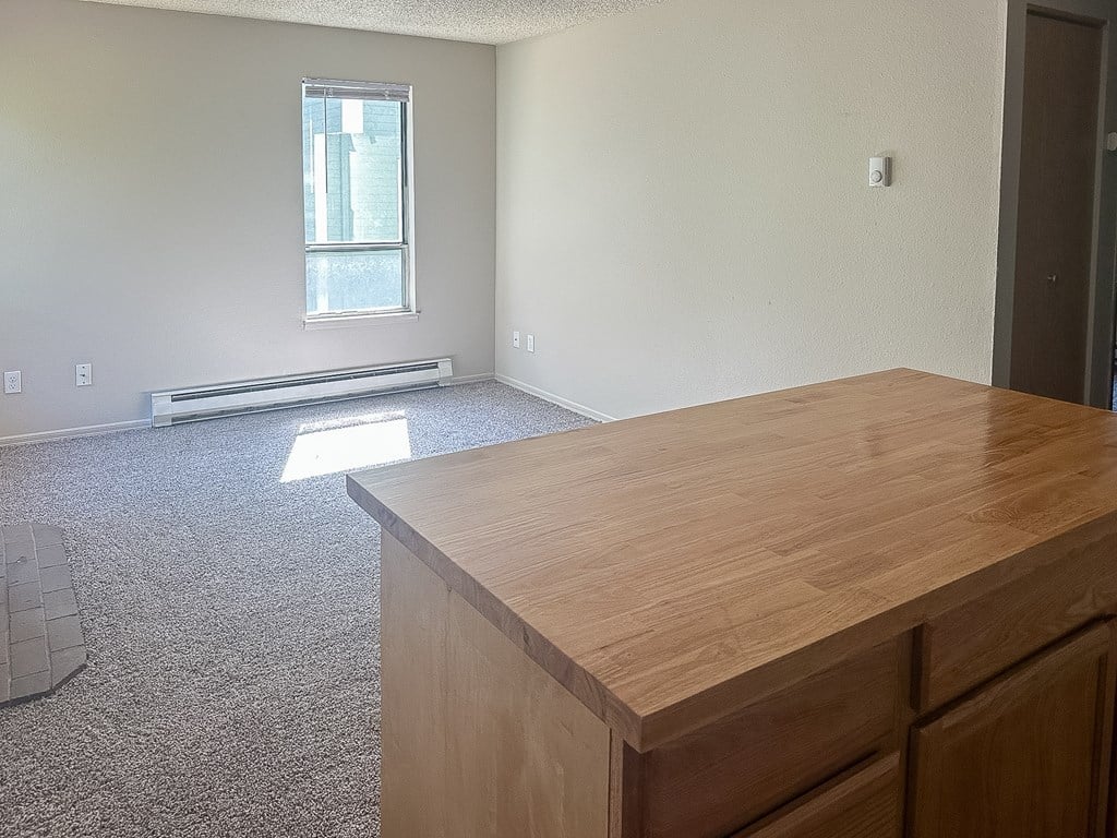 A room with a wooden desk and a window with blinds.
