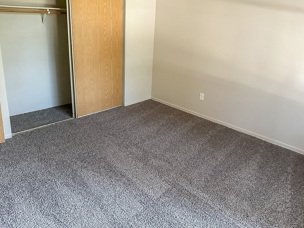 A room with a carpeted floor and a wooden door.