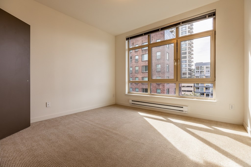 A room with a large window and a carpeted floor.