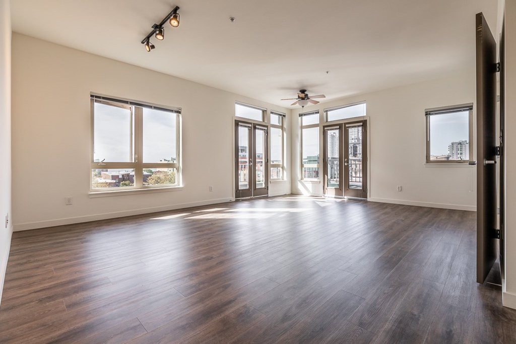 A spacious room with wooden floors and large windows.