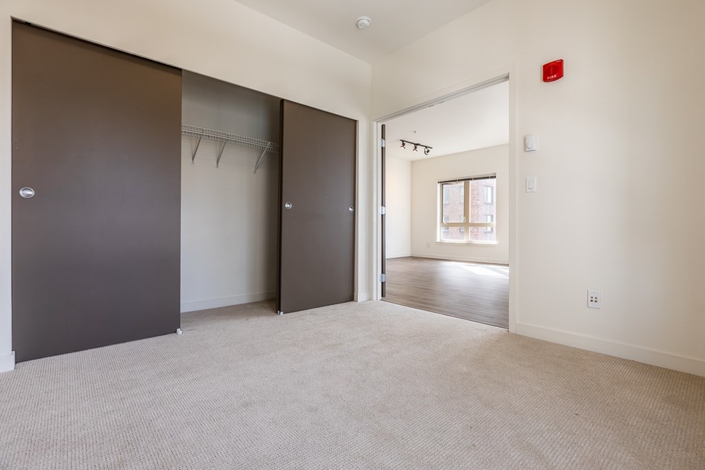 A room with a carpeted floor and a door on the left.