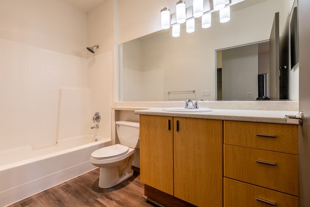 A white toilet sits in a bathroom with wooden cabinets.