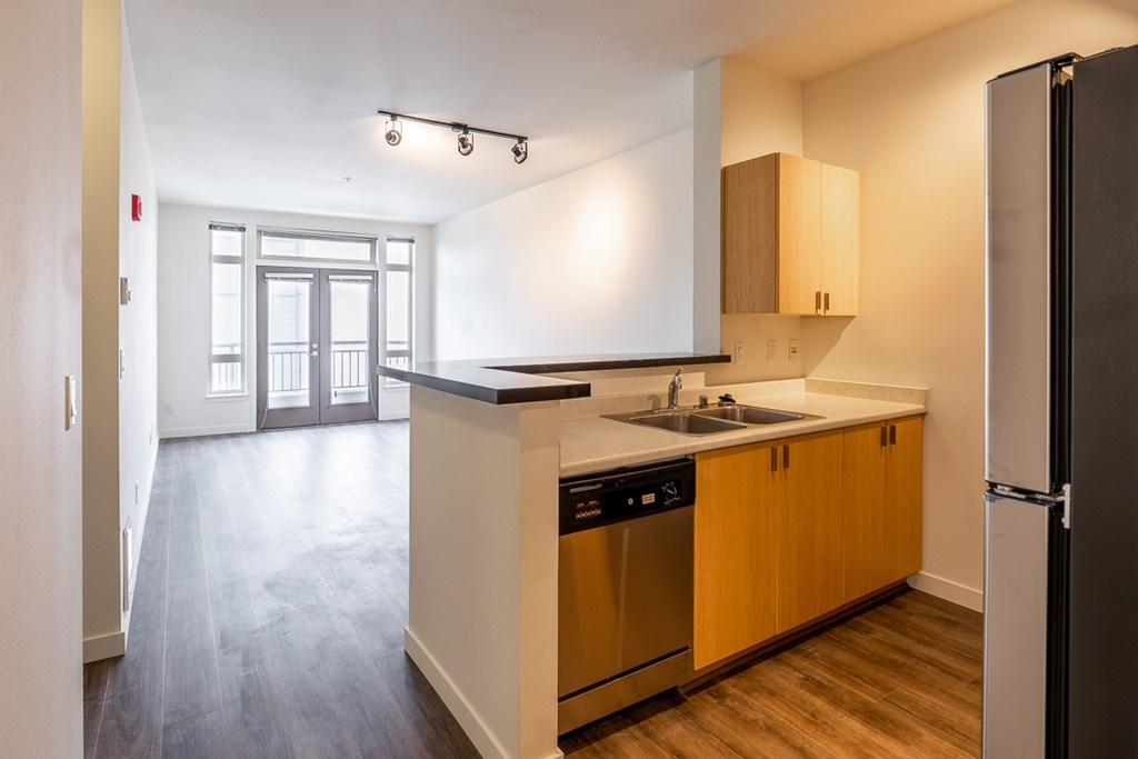 A kitchen with wooden cabinets and a black fridge.