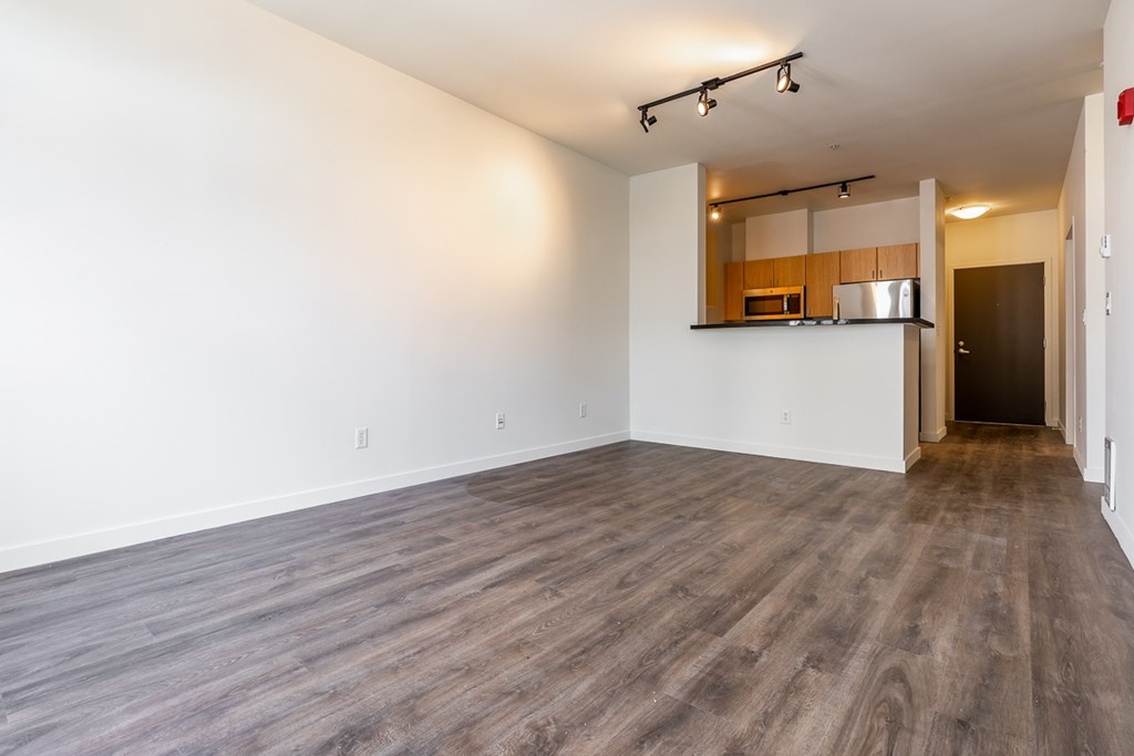 A spacious room with wooden flooring and a small kitchenette in the corner.