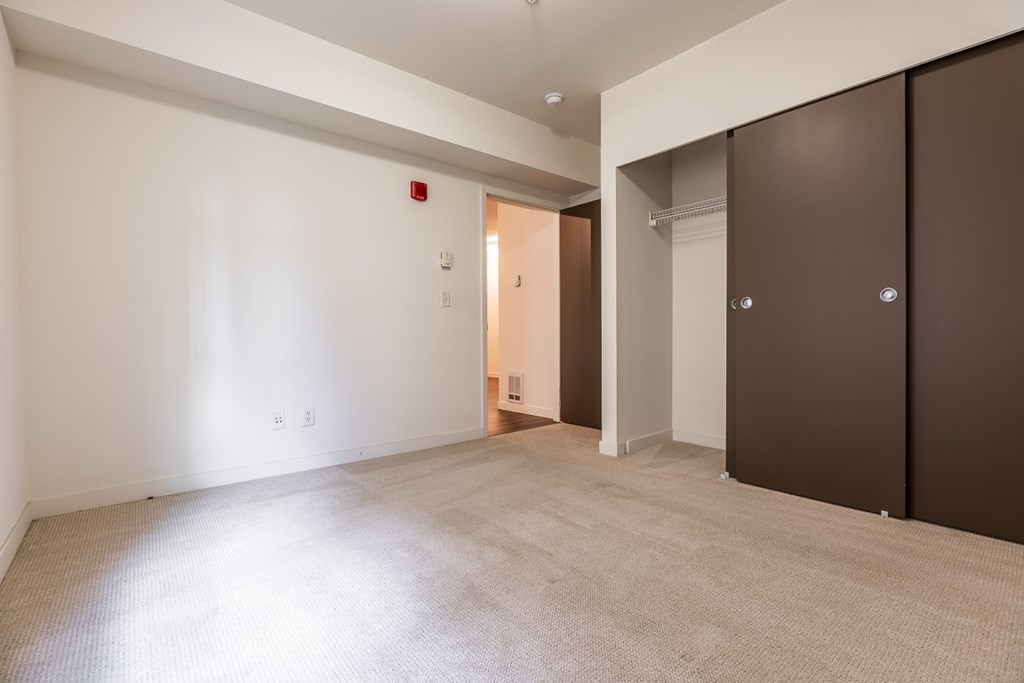 A room with a carpeted floor and a doorway leading to another room.