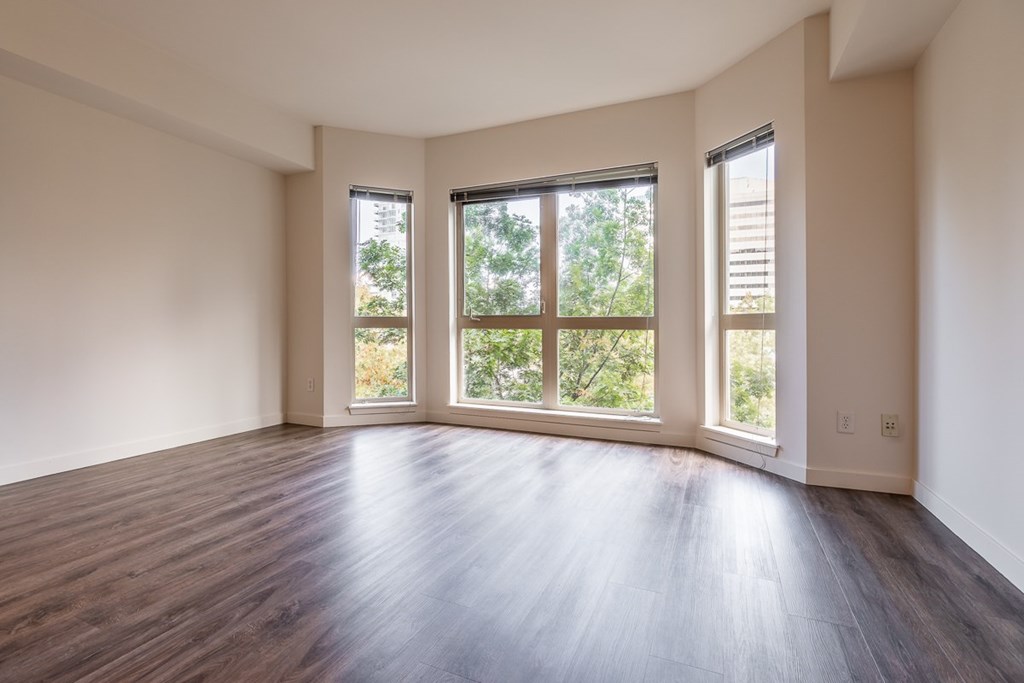 A room with wooden floors and two windows.