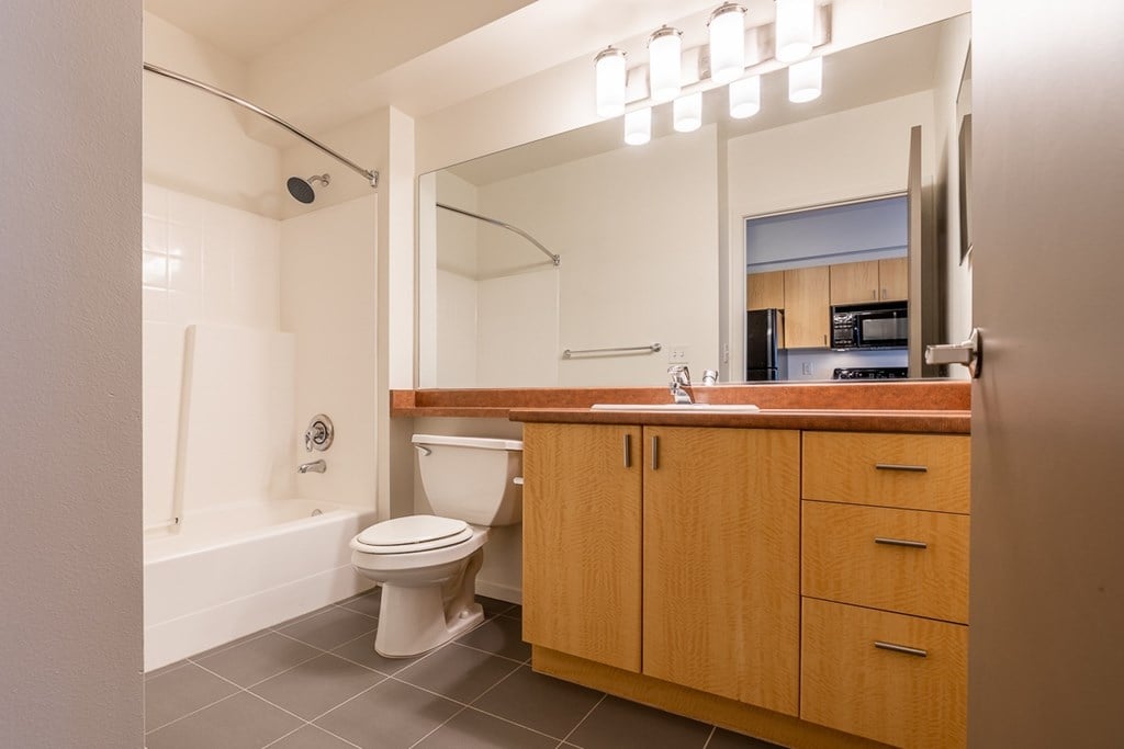 A bathroom with a toilet, sink, and mirror.