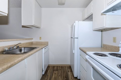 A kitchen with white appliances and wooden floors.