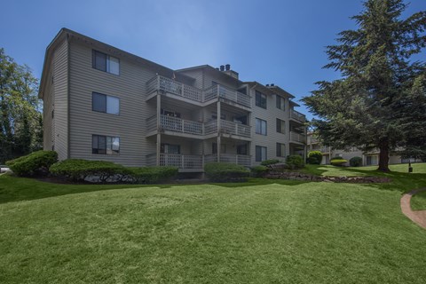A large apartment building with a green lawn in front.