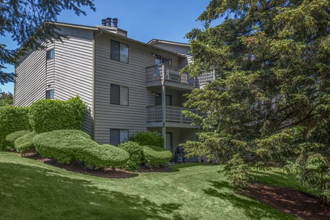 A large building with a balcony and a green lawn in front.