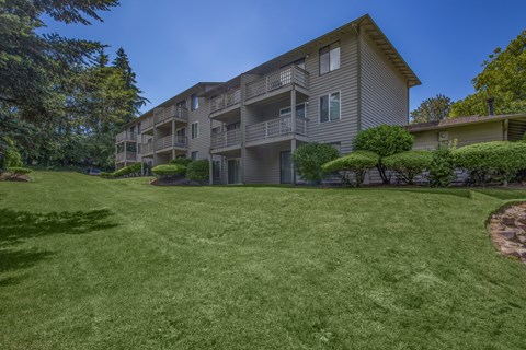 A large grassy area in front of a building with balconies.