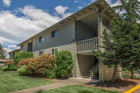 A house with a grey siding and a white roof with a staircase leading to the second floor.