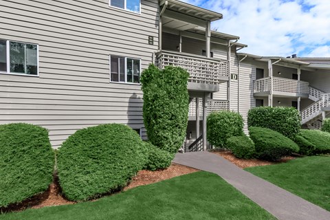 A building with a balcony and a green bush in front.