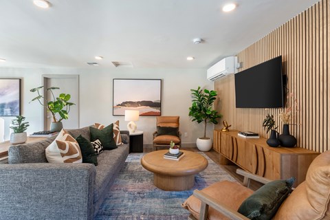 A living room with a grey couch, a wooden coffee table, and a large painting on the wall.