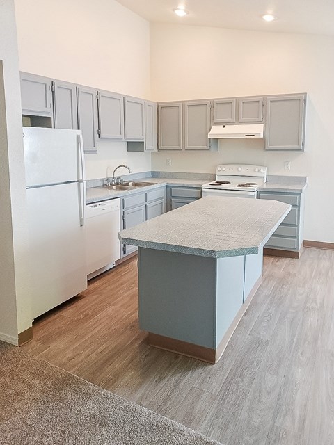 A kitchen with a white refrigerator and a countertop island.