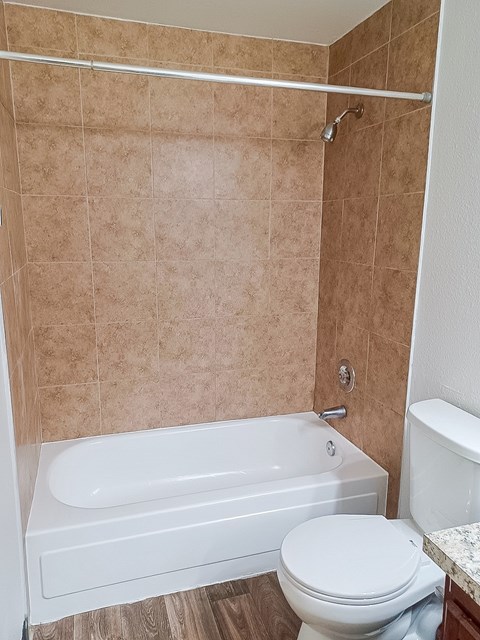 A white toilet sits next to a bathtub in a bathroom.