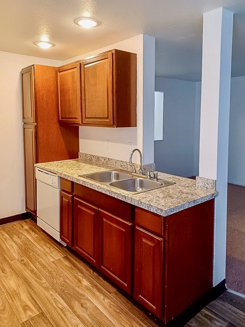 A kitchen with wooden cabinets and a white dishwasher.