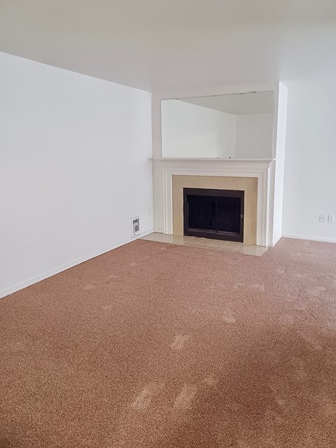 A room with a fireplace and carpeted floor.