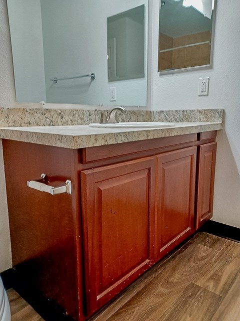 A bathroom with a brown cabinet and a marble counter.