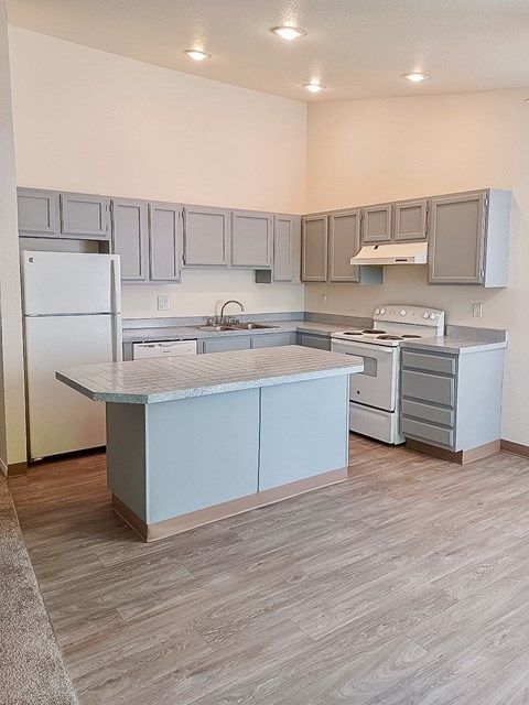 A kitchen with a white refrigerator and a marble island.
