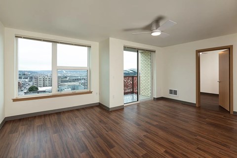 A room with a ceiling fan and a view of the city.