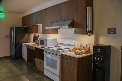 A kitchen with a white stove top oven and a black refrigerator.
