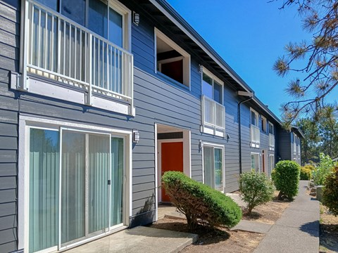 A row of houses with grey siding and red doors.