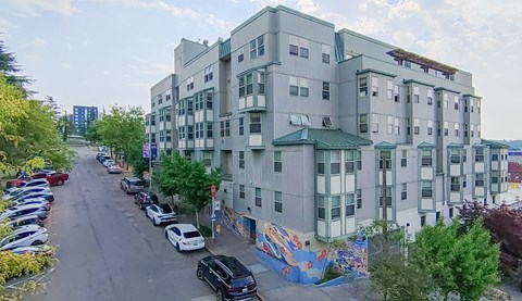 A street view of a residential area with apartment buildings and parked cars.