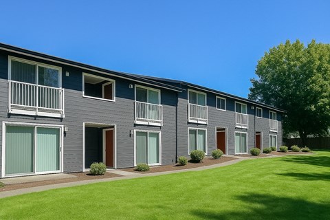 A row of grey houses with green lawns in front.