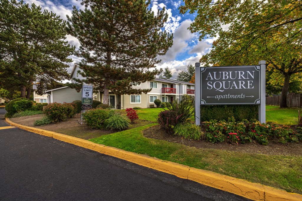 A sign for Auburn Square apartments is in front of a building.