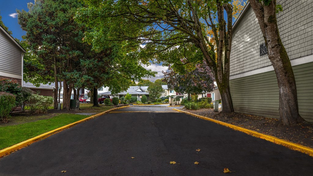 A residential street with houses on both sides and trees lining the road.