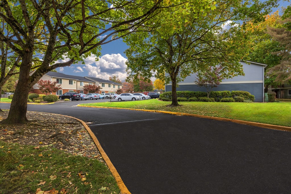 A tree-lined street with cars parked on the side.