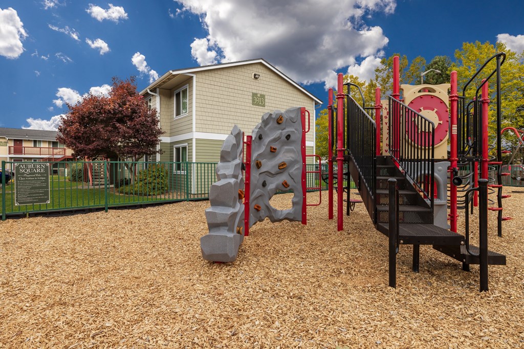 A playground with a slide, climbing wall, and a rock climbing wall.
