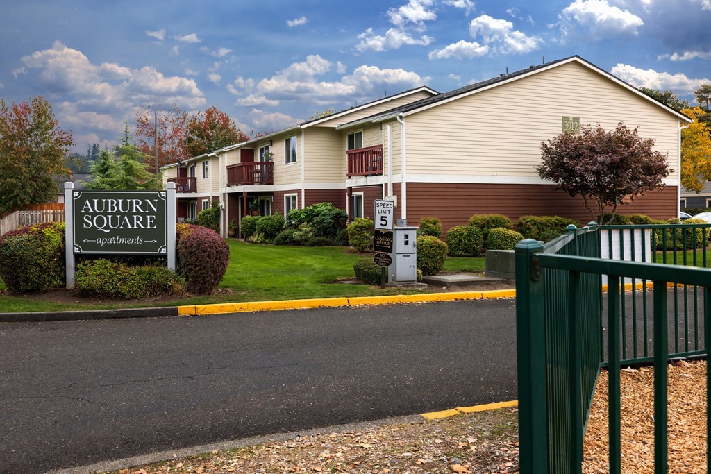 A brown building with a sign that says Auburn Square in front of it.