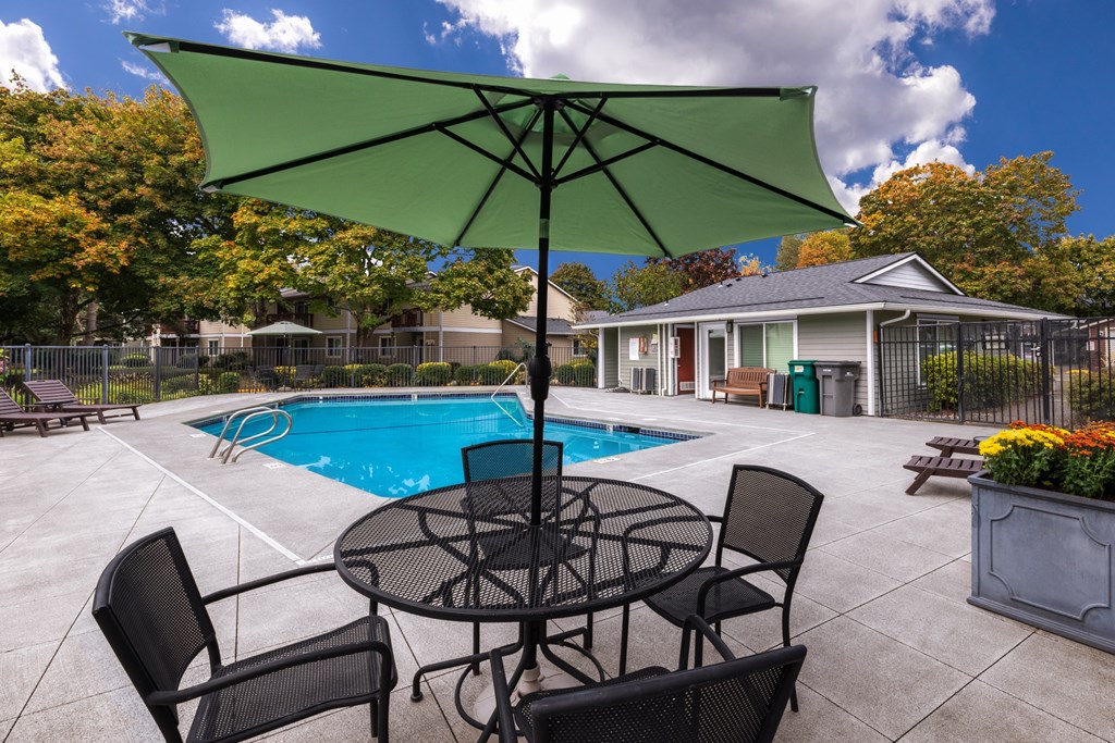 A patio with a table and chairs and a pool.