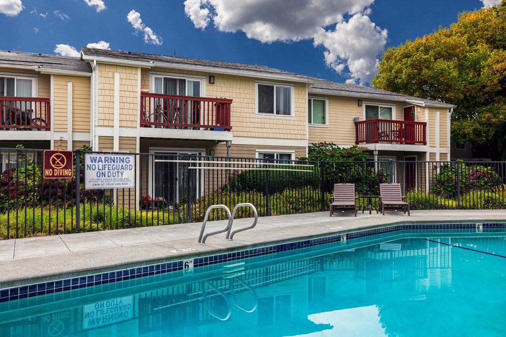 A pool in front of a building with a warning sign.