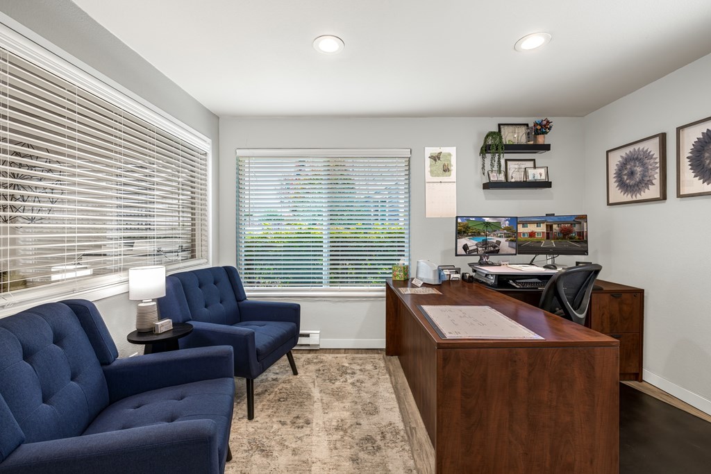 A room with two blue chairs and a wooden desk.