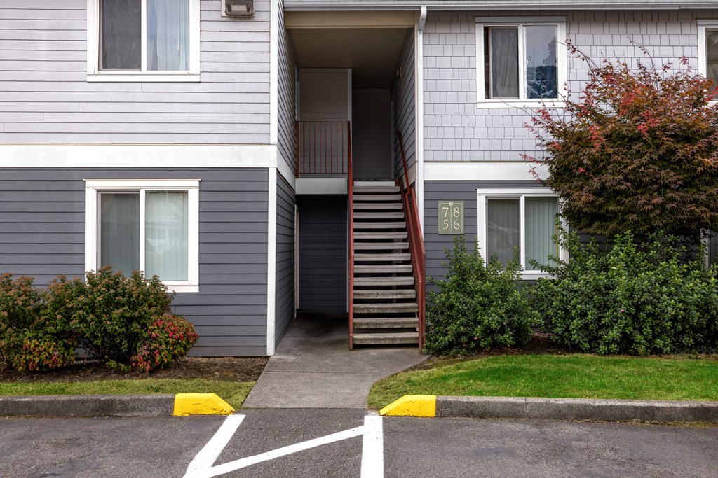 A grey building with a staircase leading to the entrance.