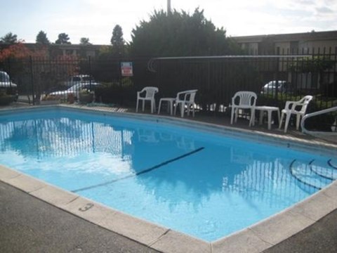 A pool with chairs around it and a sign in the background.