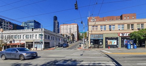 A street view with a car on the road and buildings on the side.