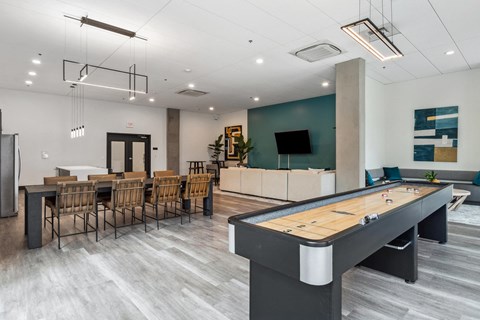 A pool table is in the middle of a room with a bar and chairs.