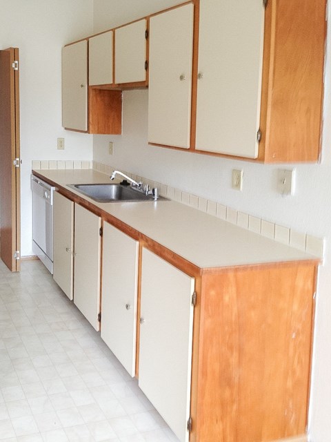 A kitchen with wooden cabinets and a white counter.
