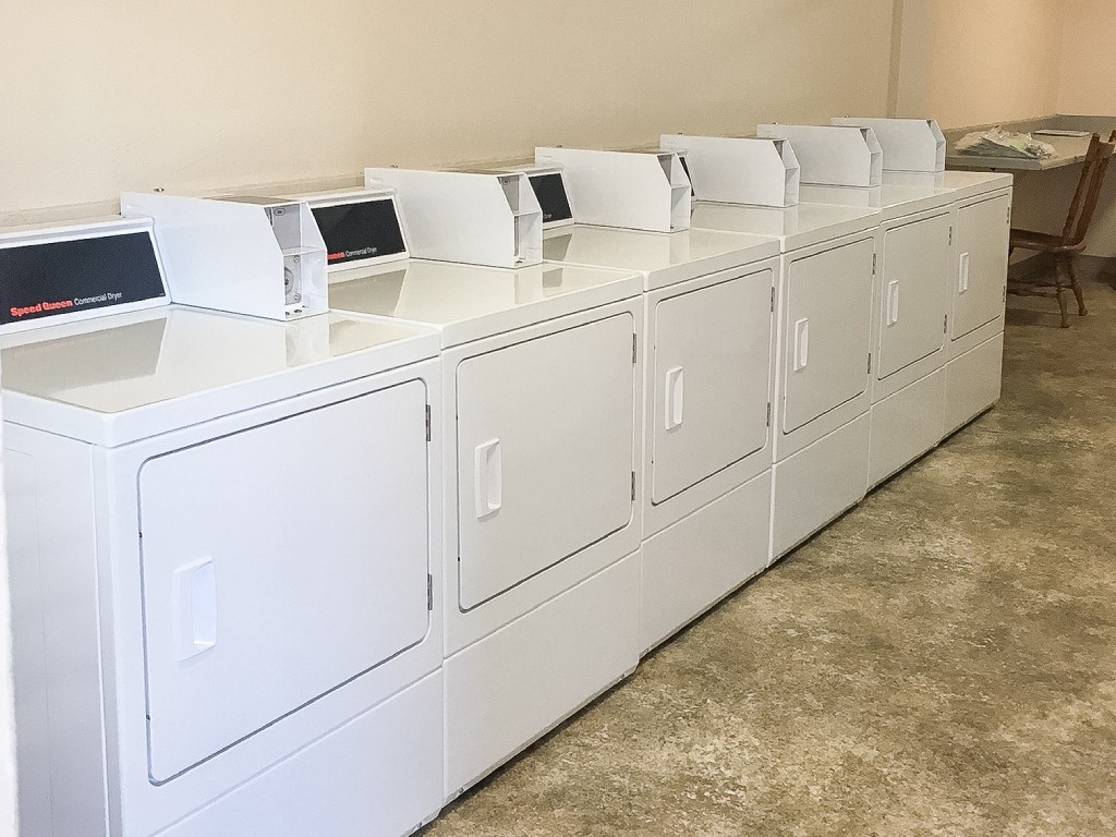 A row of white washing machines are lined up in a room.