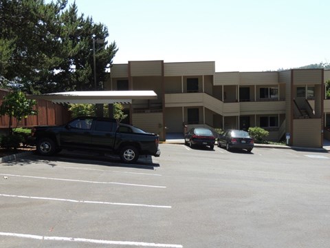 A black truck is parked in a parking lot in front of a building.
