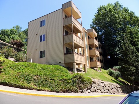 A beige apartment building with a green lawn in front.